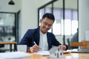 A happy man holding a pen and ready to sign on a home insurance document